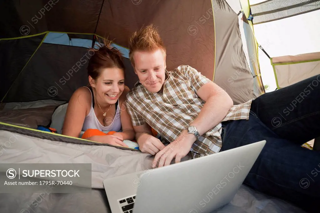 Hikers in tent using laptop