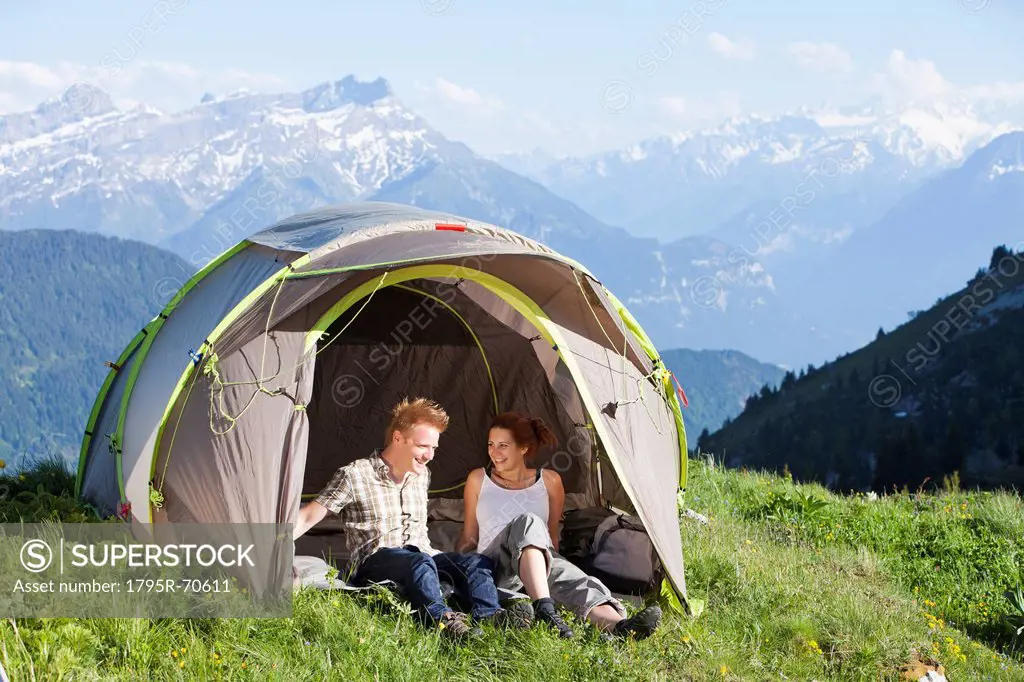 Switzerland, Leysin, Hikers resting in tent pitched on meadow
