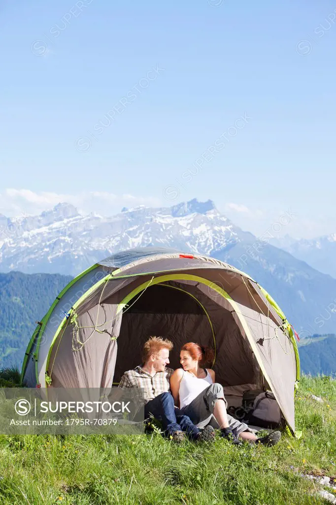 Switzerland, Leysin, Hikers resting in tent pitched on meadow
