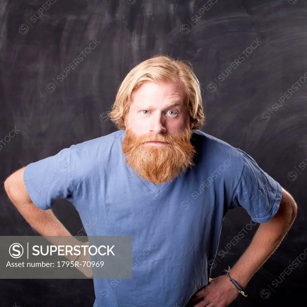 Man standing in front of blackboard staring at camera