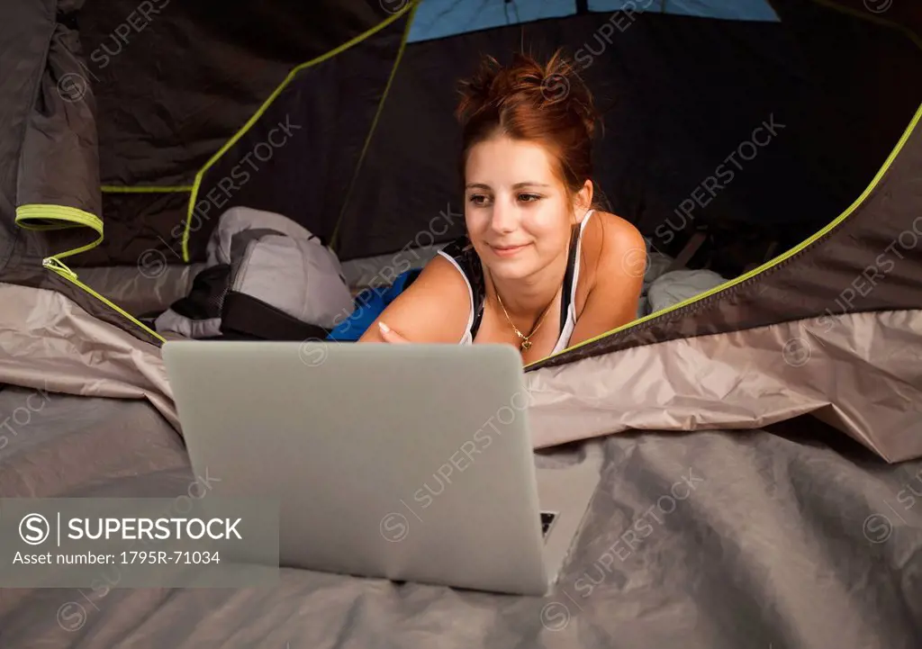 Hiker in tent using laptop