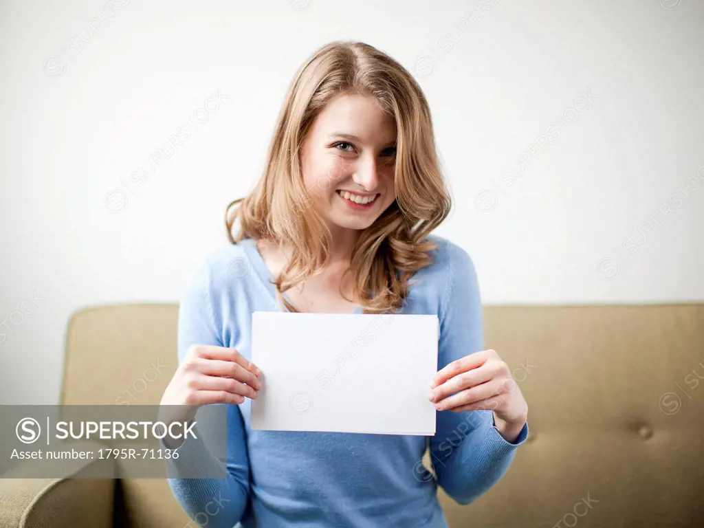 Smiling woman holding white page
