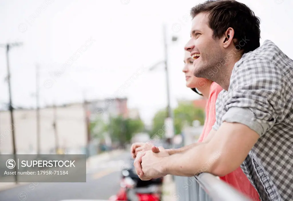 USA, New Jersey, Jersey City, Profile of happy young couple leaning on fence