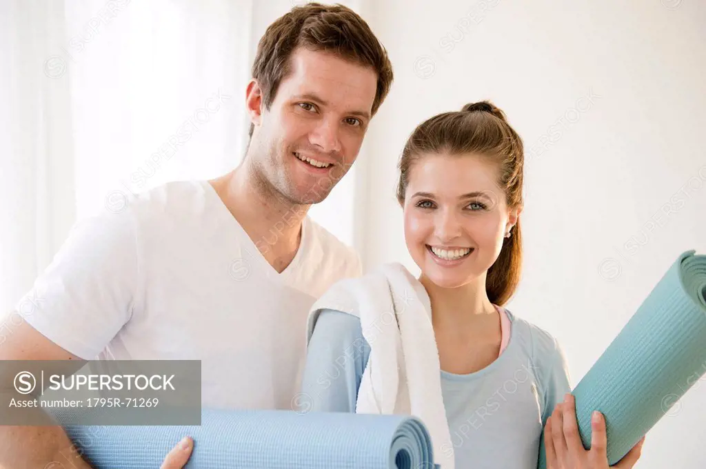 Happy young couple posing with exercising mats
