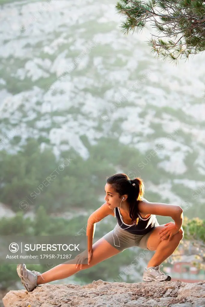 France, Marseille, Young woman stretching on cliff