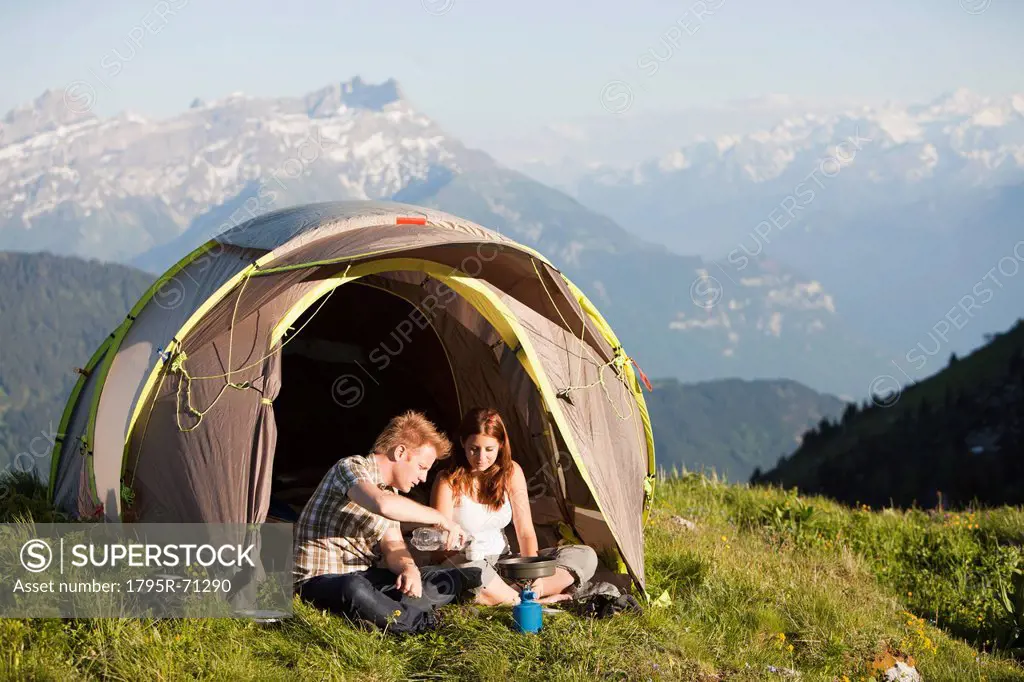 Switzerland, Leysin, Hikers preparing breakfast on Alpine meadow