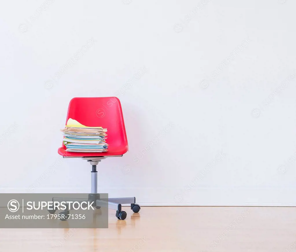 Studio shot of stack of books on red office chair