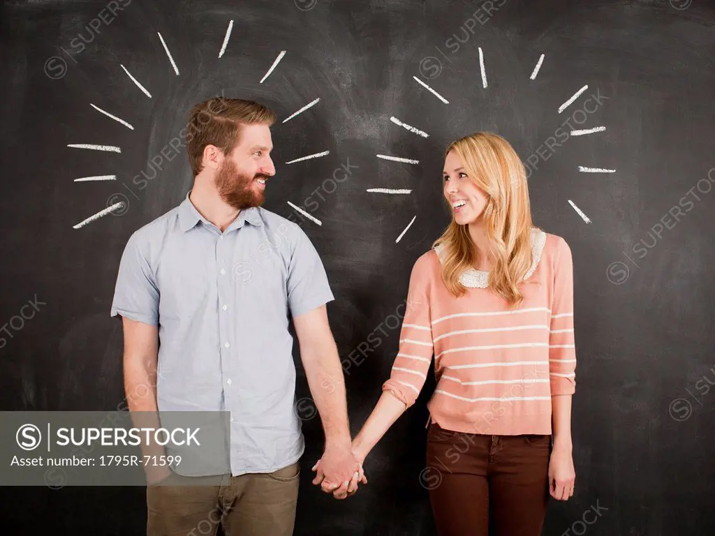 Young couple with blackboard in background, studio shot