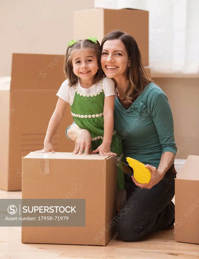 Portrait of mother with daughter 4_5 surrounded by cardboard boxes