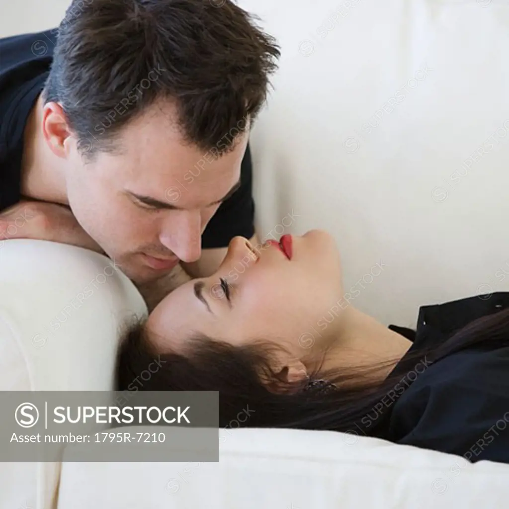 Man leaning over girlfriend on sofa