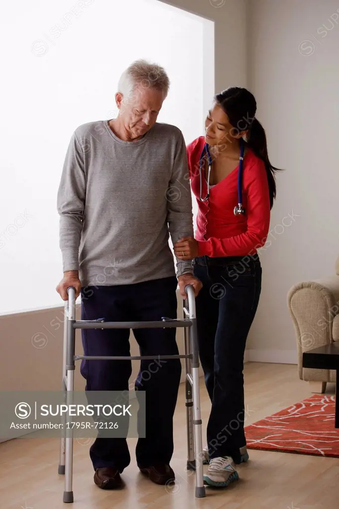 Young female nurse taking care of senior man with walker
