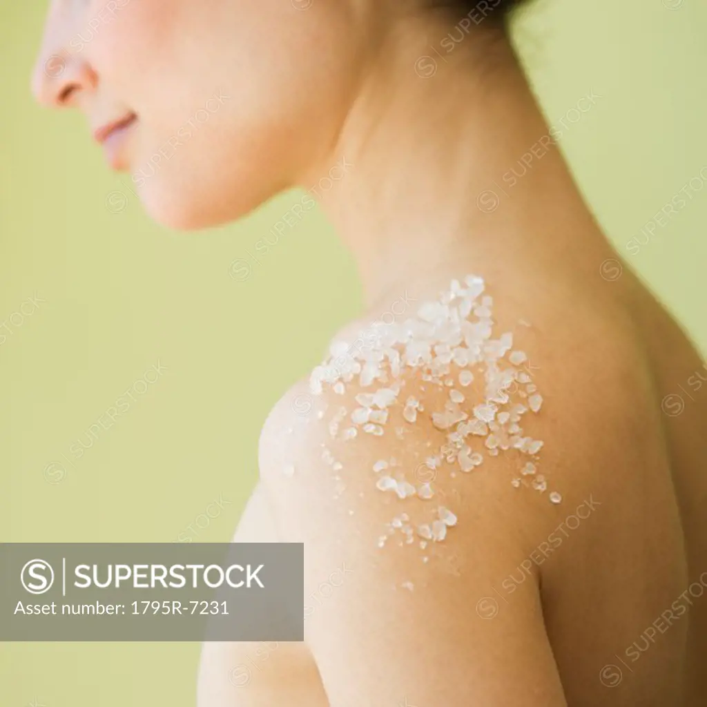 Nude woman with spa salt treatment on shoulder