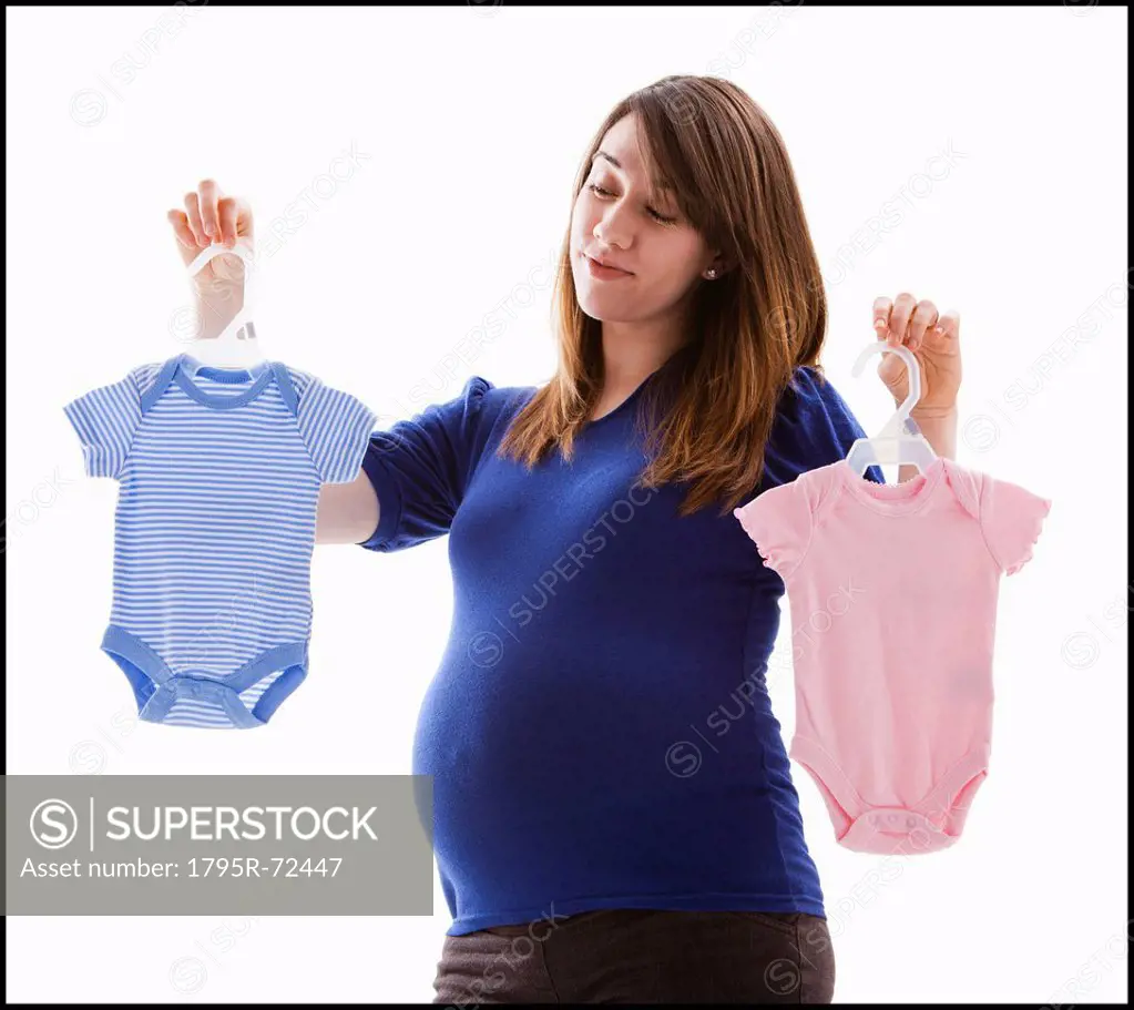 Studio Shot of pregnant woman holing baby onesie