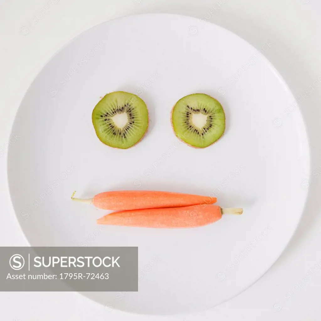 Fruit and vegetable face on plate, studio shot