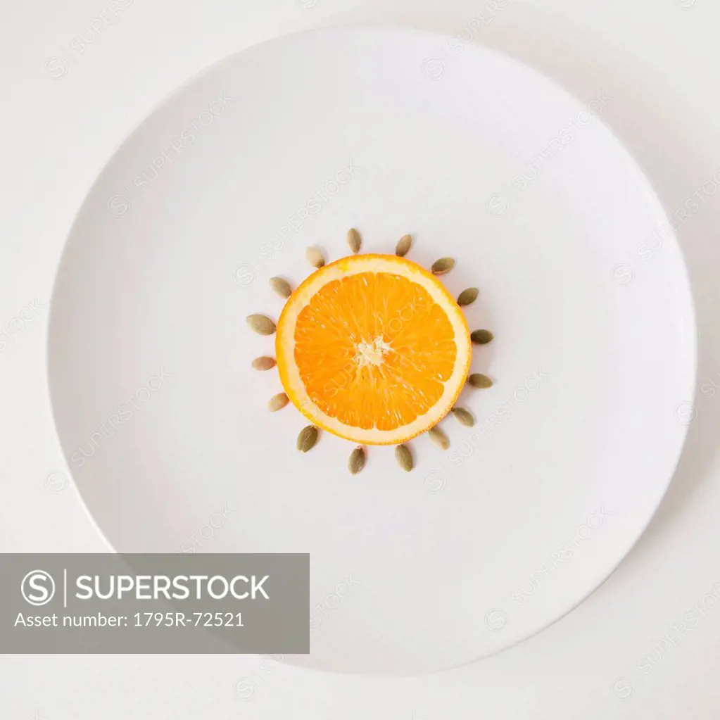 Slice of orange and seeds on plate, studio shot