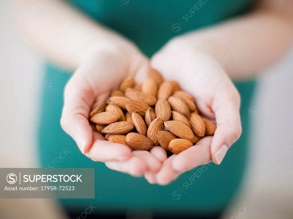 Studio shot of woman showing handful of almonds