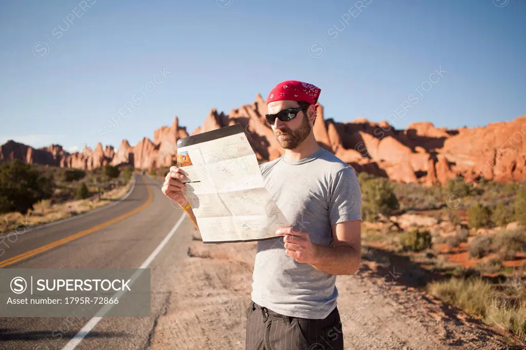 USA, Utah, Moab, Man standing on roadside, reading map