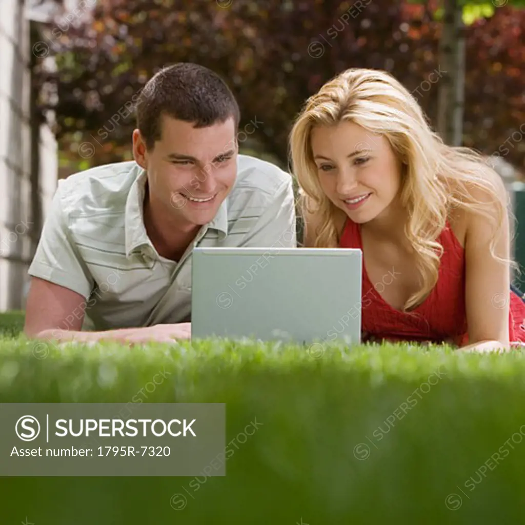 Couple using laptop in grass