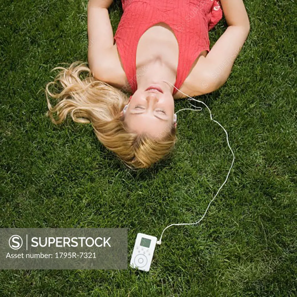 Woman listening to mp3 player in grass