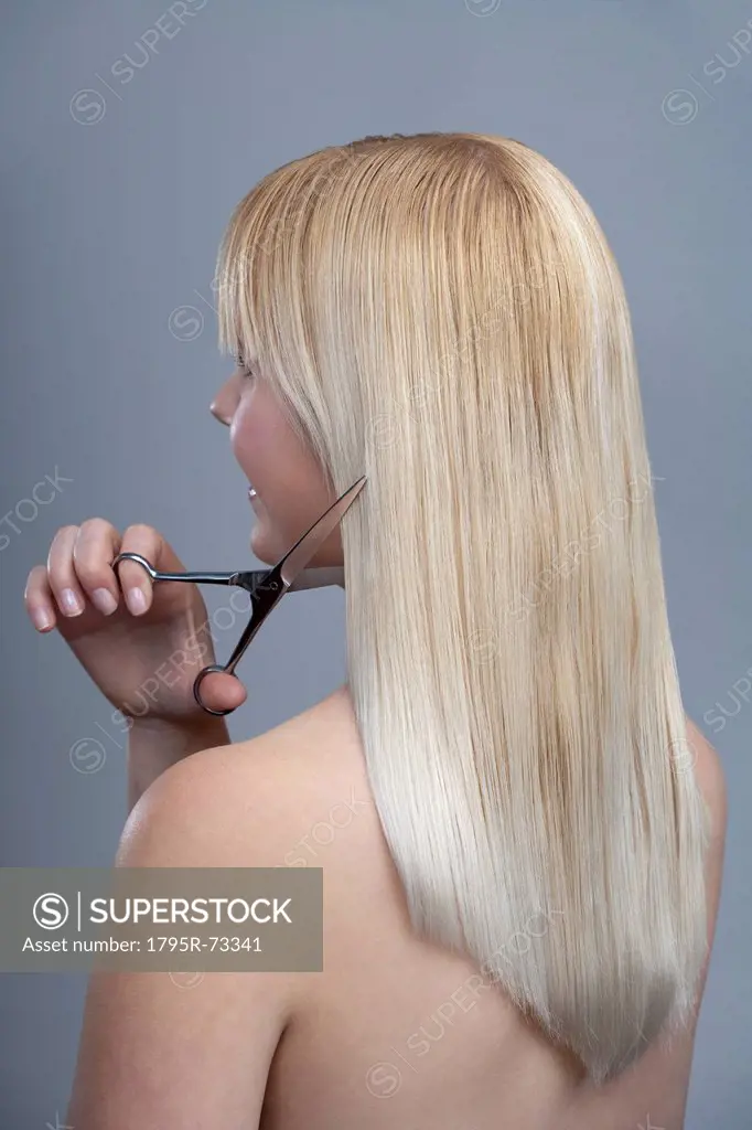 Woman cutting hair, studio shot