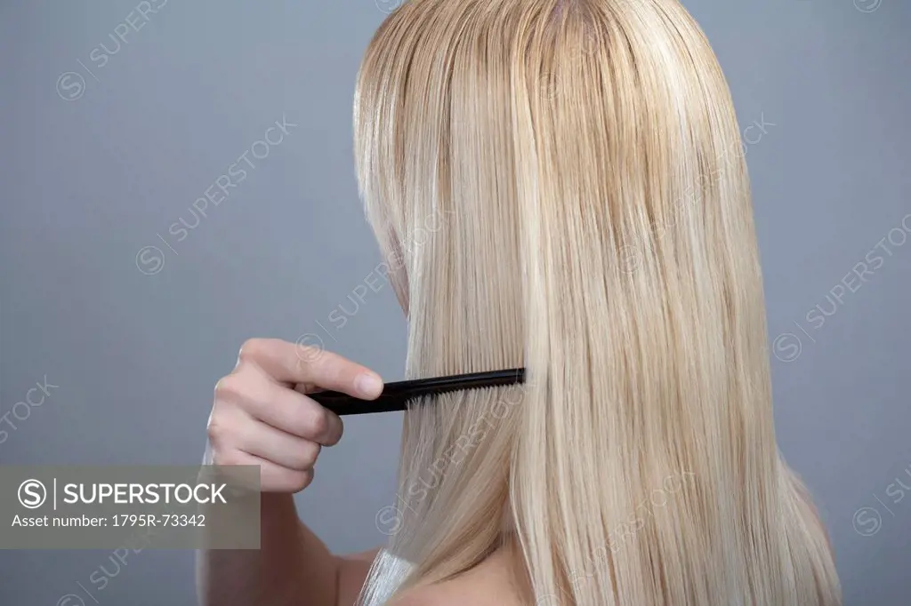 Woman combing hair, studio shot