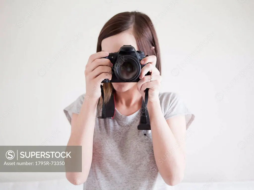 Young woman playing with digital camera