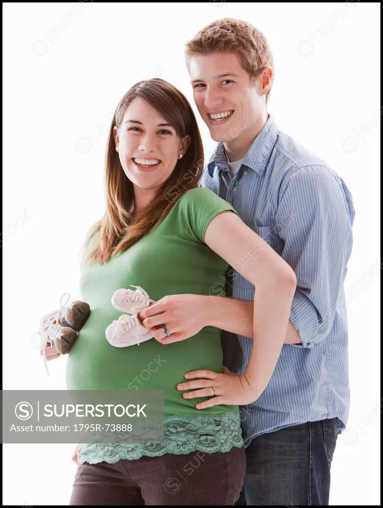 Man embracing pregnant woman, studio shot