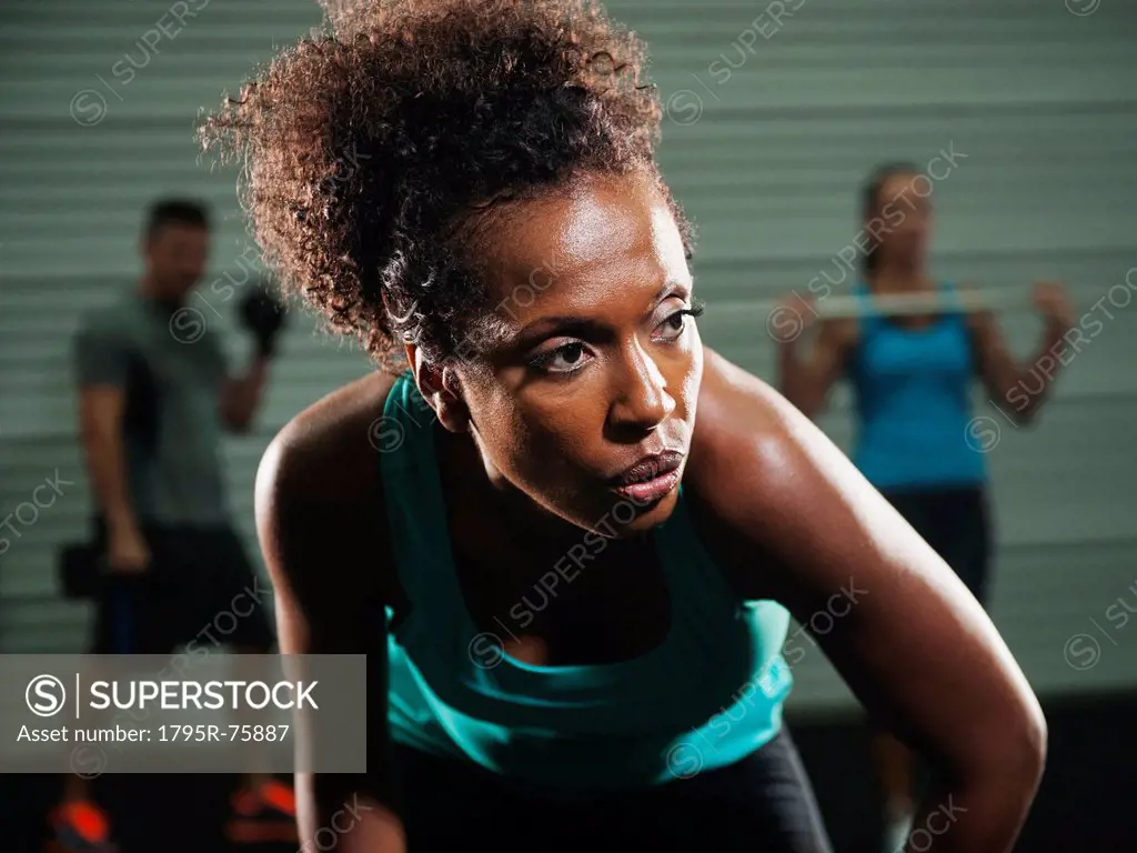 Portrait of mid adult woman in gym with people exercising in background