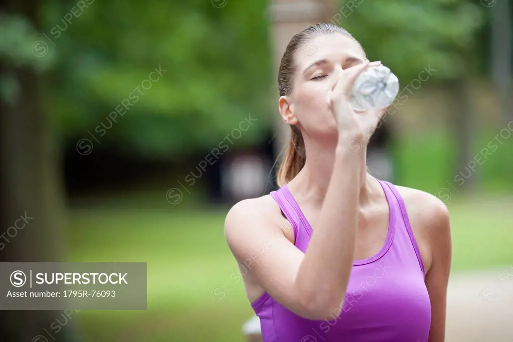 Young woman drinking water from bottle after running