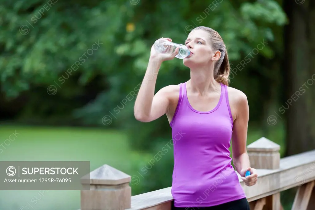 Young woman drinking water from a bottle after running