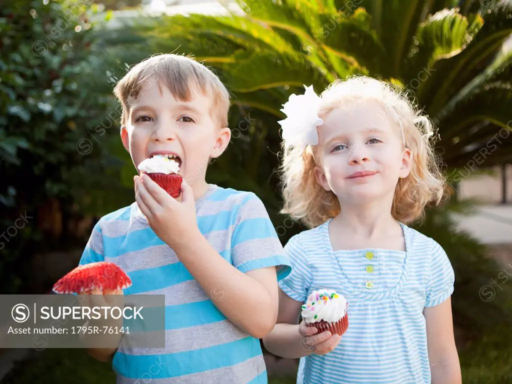 Girl and boy eating cupcakes