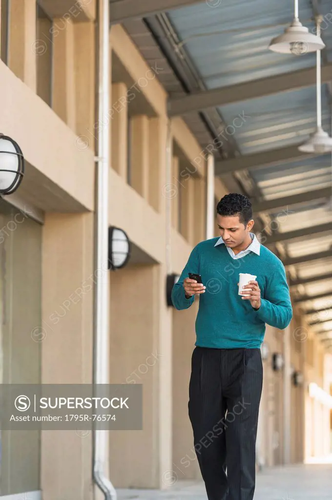 Man walking outside building and text messaging