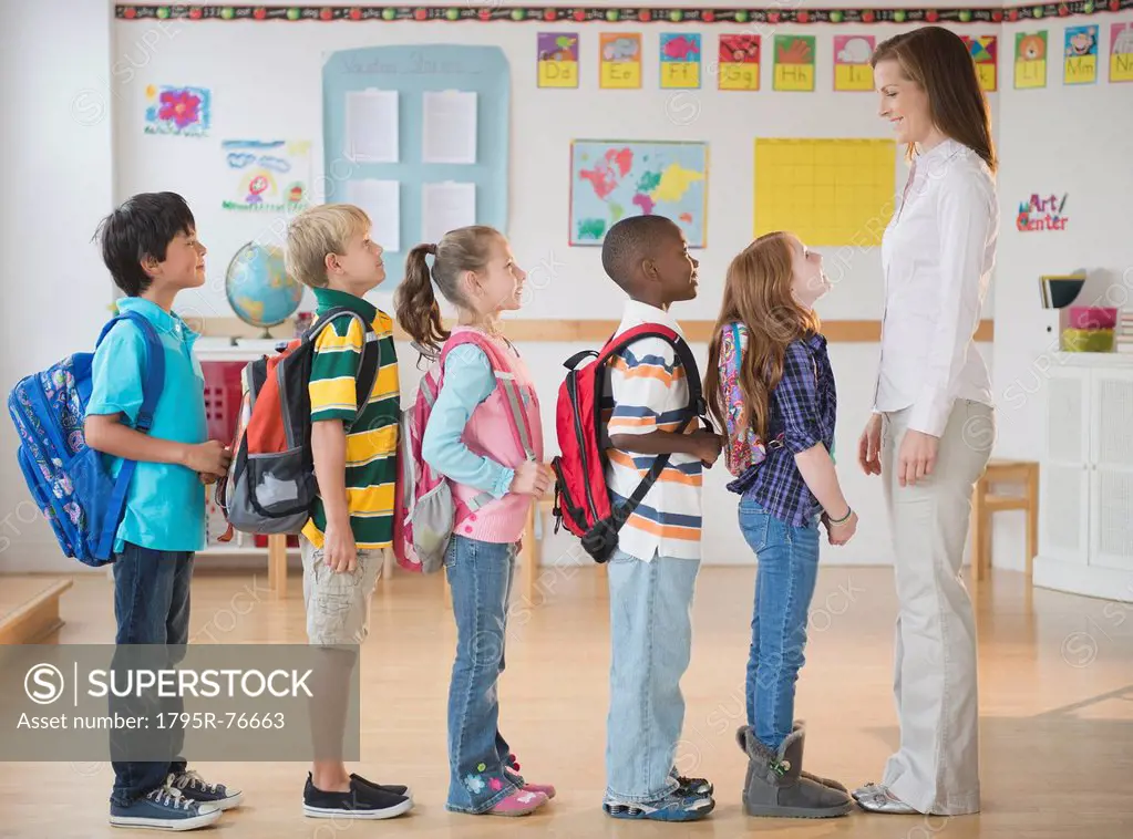 School children 8_9 with female teacher standing in row in classroom