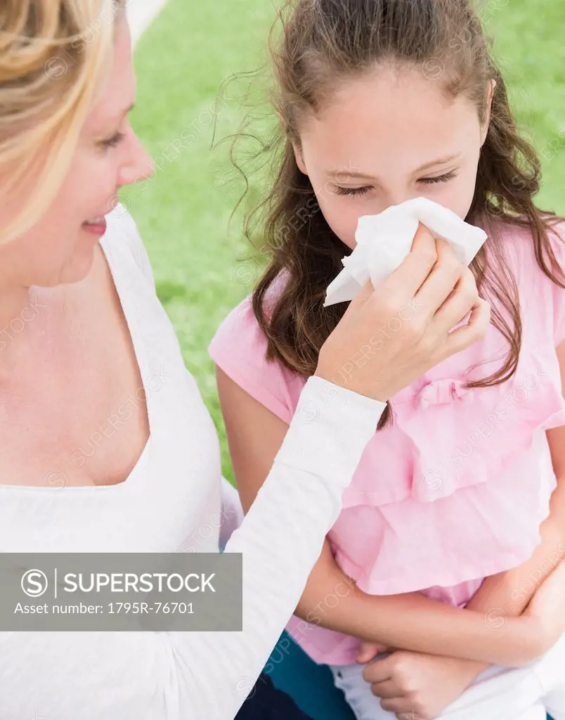 Mother helping daughter 8_9 years to blow her nose