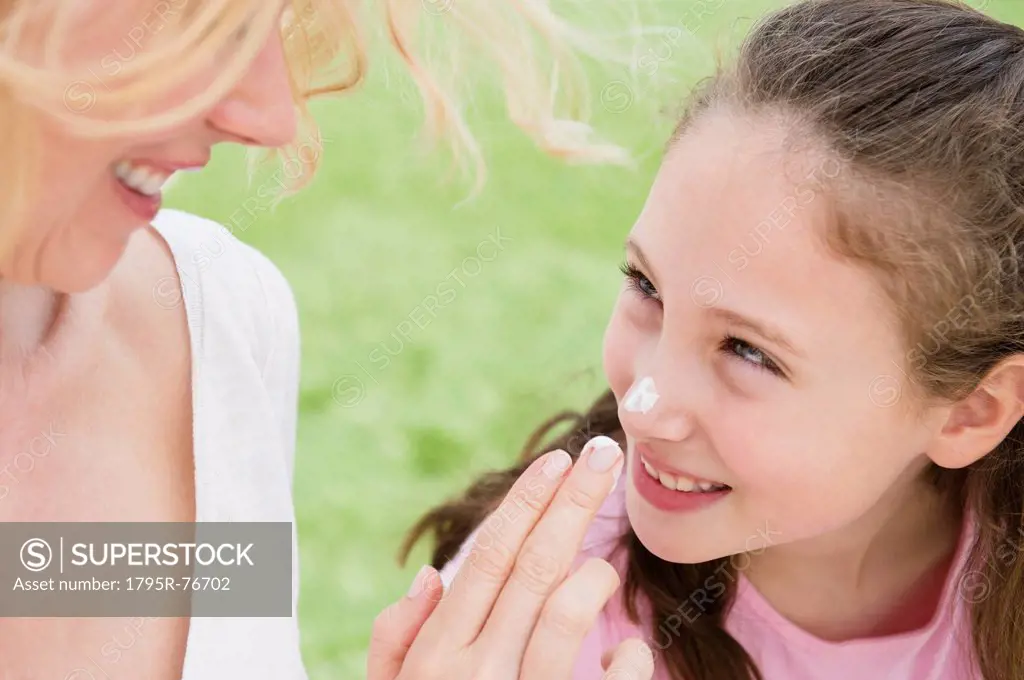 Mother applying moisturizer on daughter´s 8_9 years nose