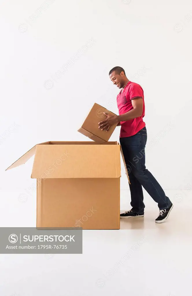 Studio shot of young man with large cardboard box