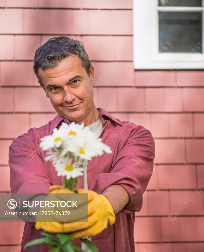 Portrait of man giving bunch of flowers