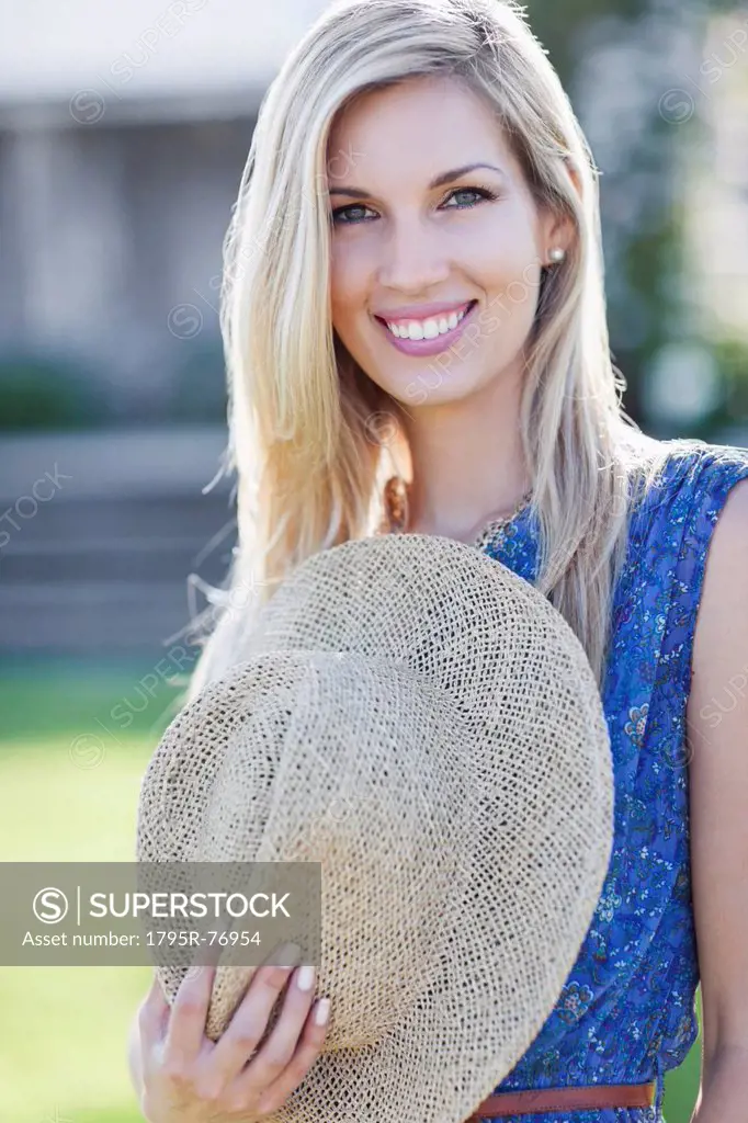 Portrait of smiling woman holding straw hat