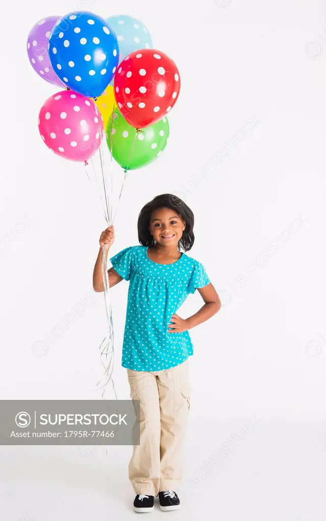 Studio shot of girl 6_7 years holding colorful balloons