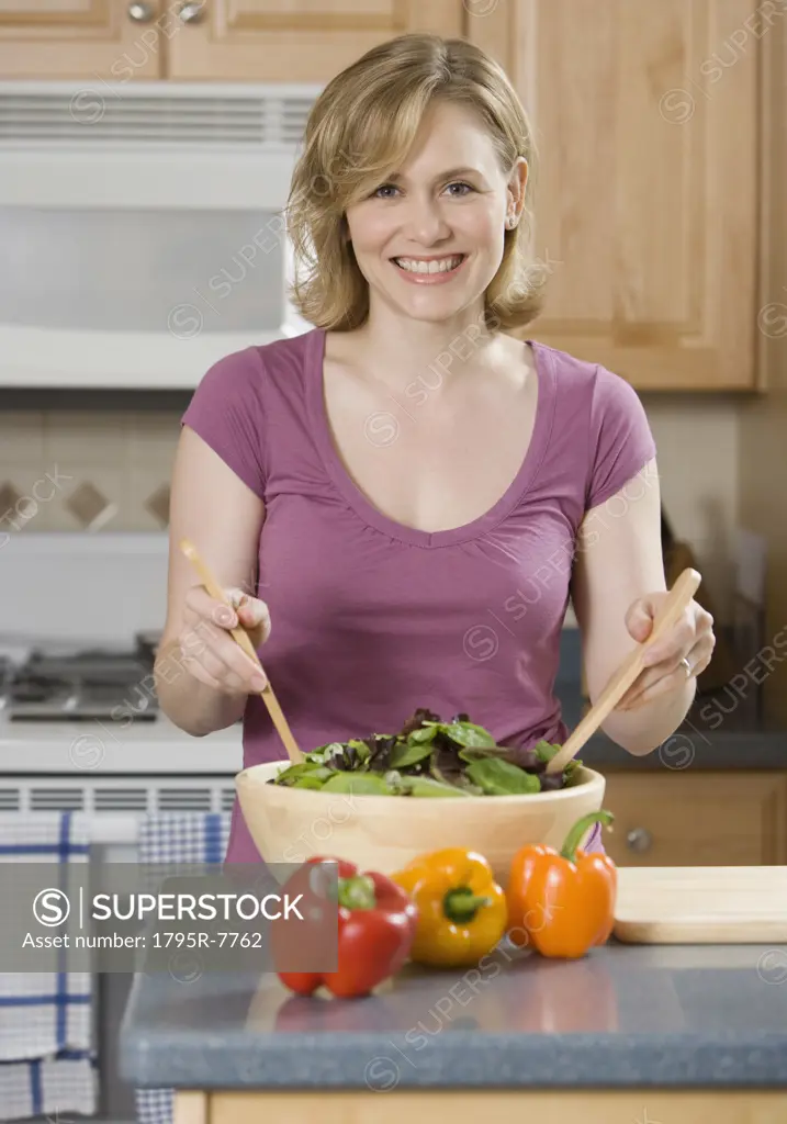 Woman tossing salad in kitchen
