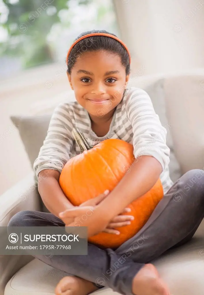 Portrait of smiling girl 6_7 sitting on sofa with pumpkin