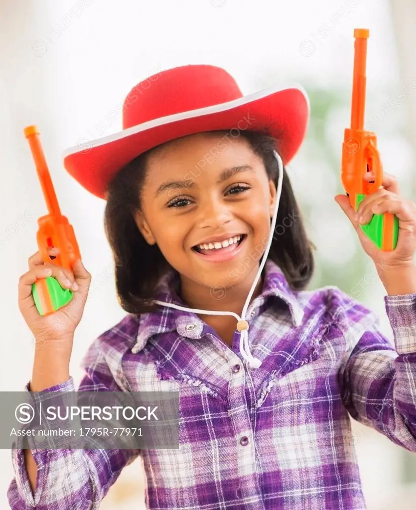 Portrait of smiling girl 6_7 with cowboy hat and toy gun