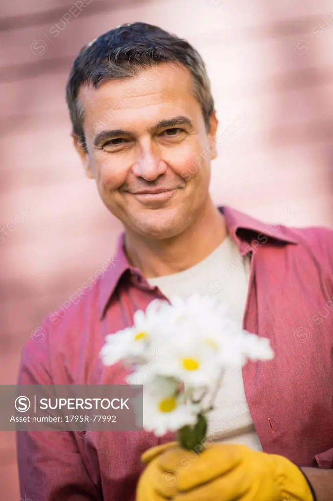 Portrait of smiling man holding flowers