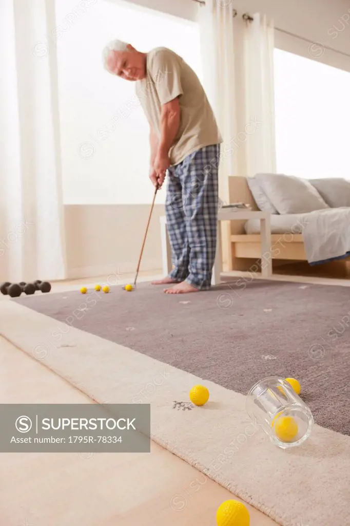 Senior man playing mini golf at home
