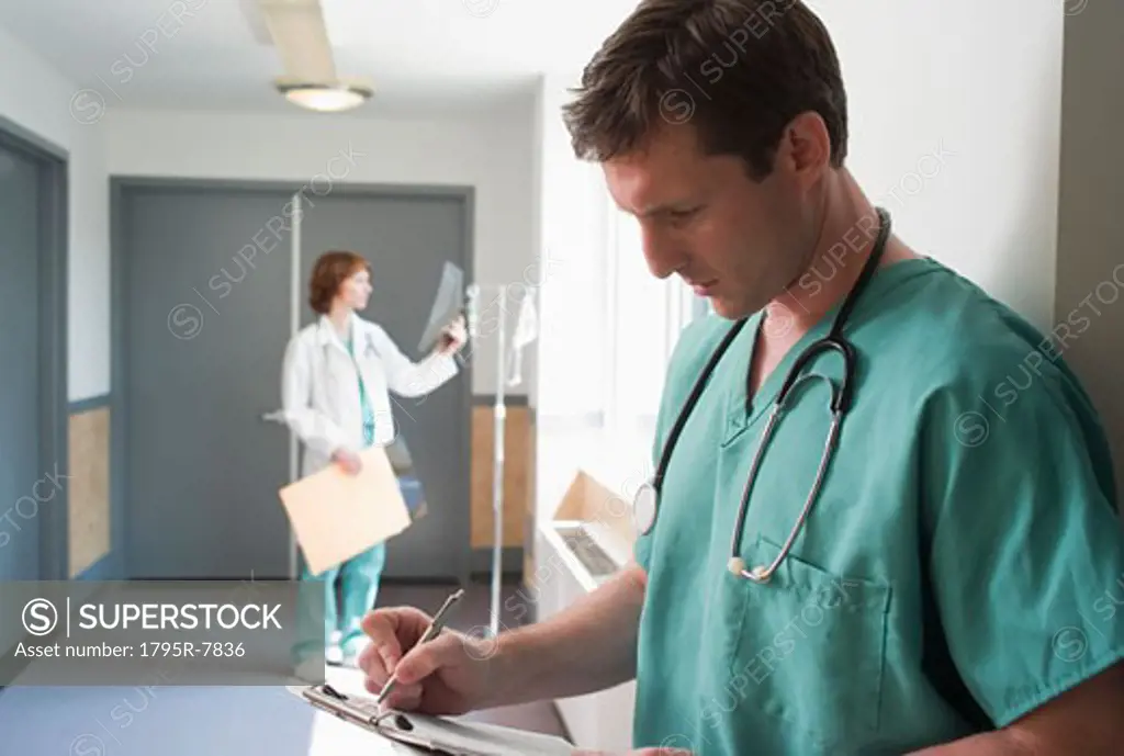 Male doctor writing on chart