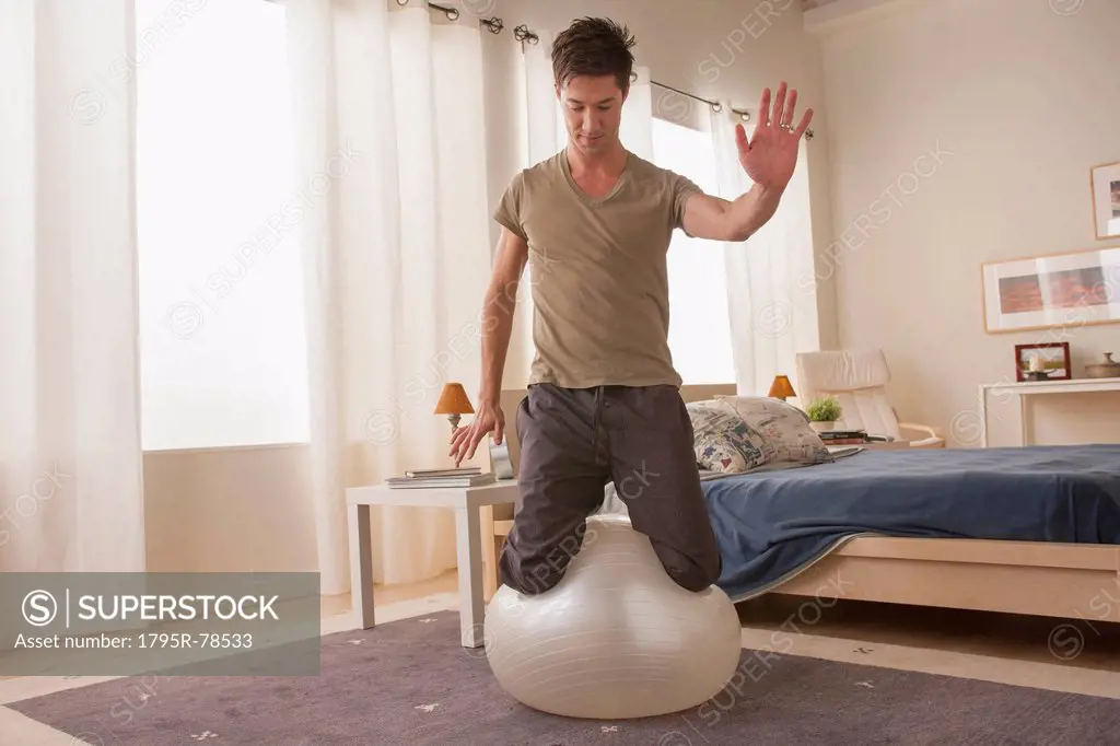 Man kneeling on top of fitness ball