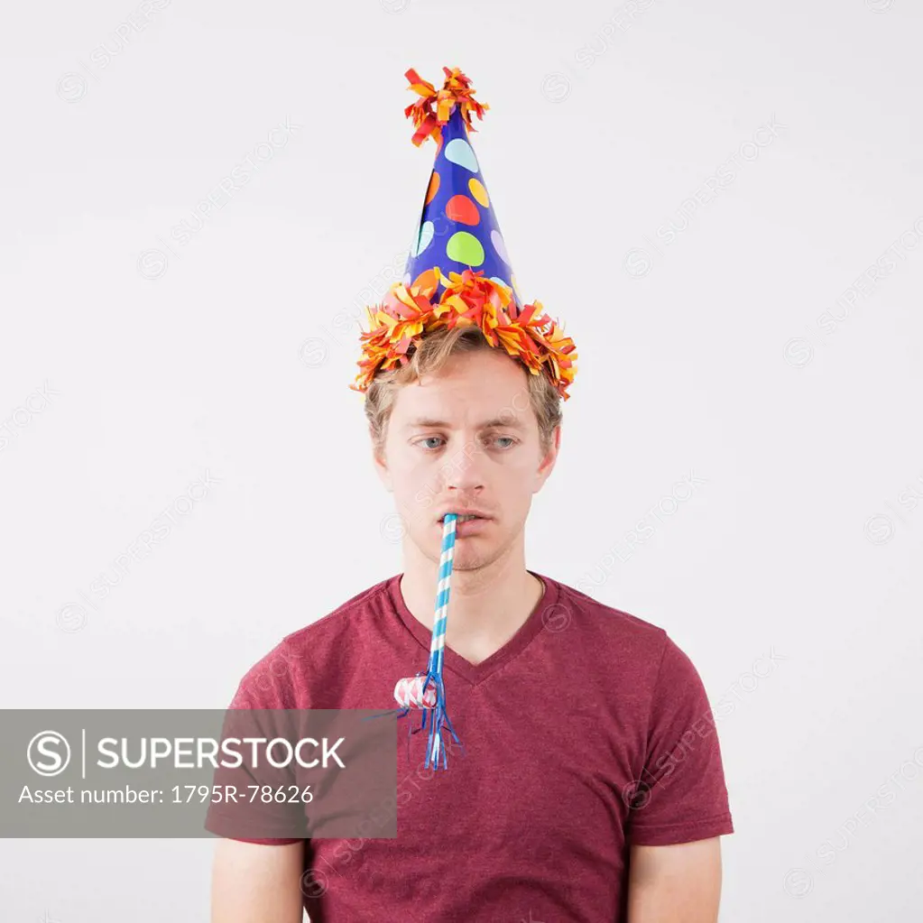 Displeased man with party hat and party horn blower