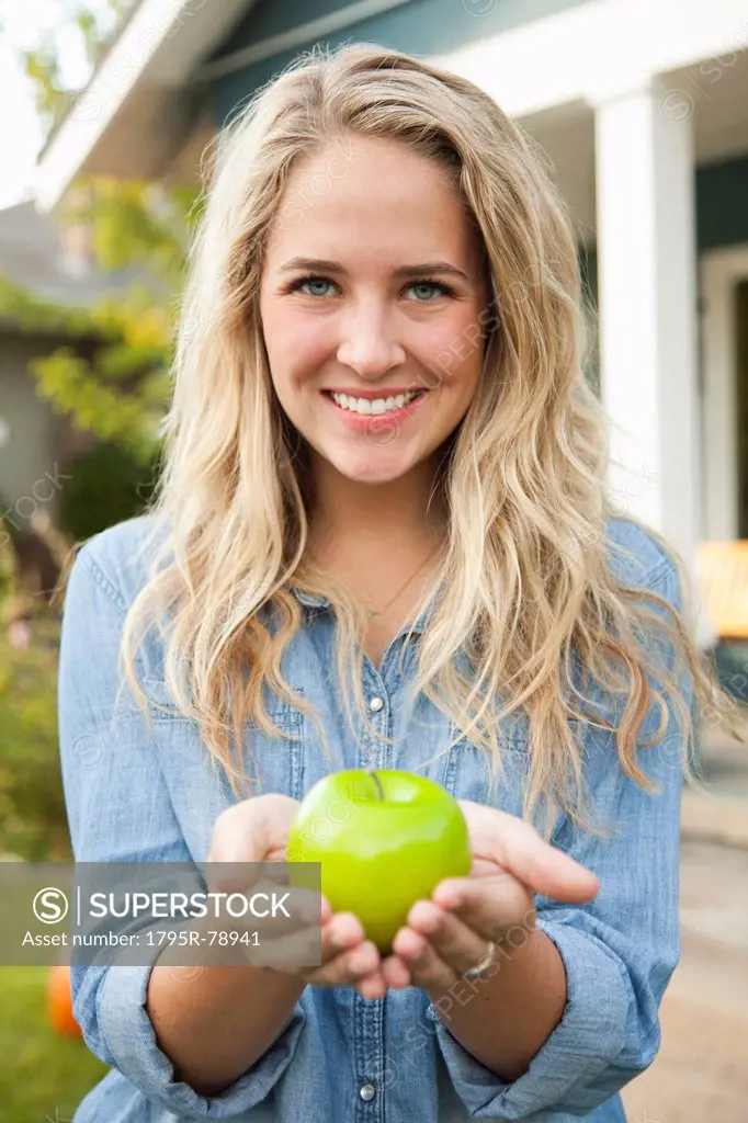 Portrait of young woman holding green apple