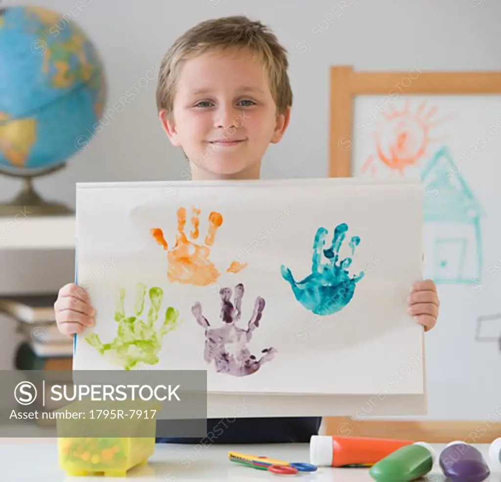 Boy holding handprint painting