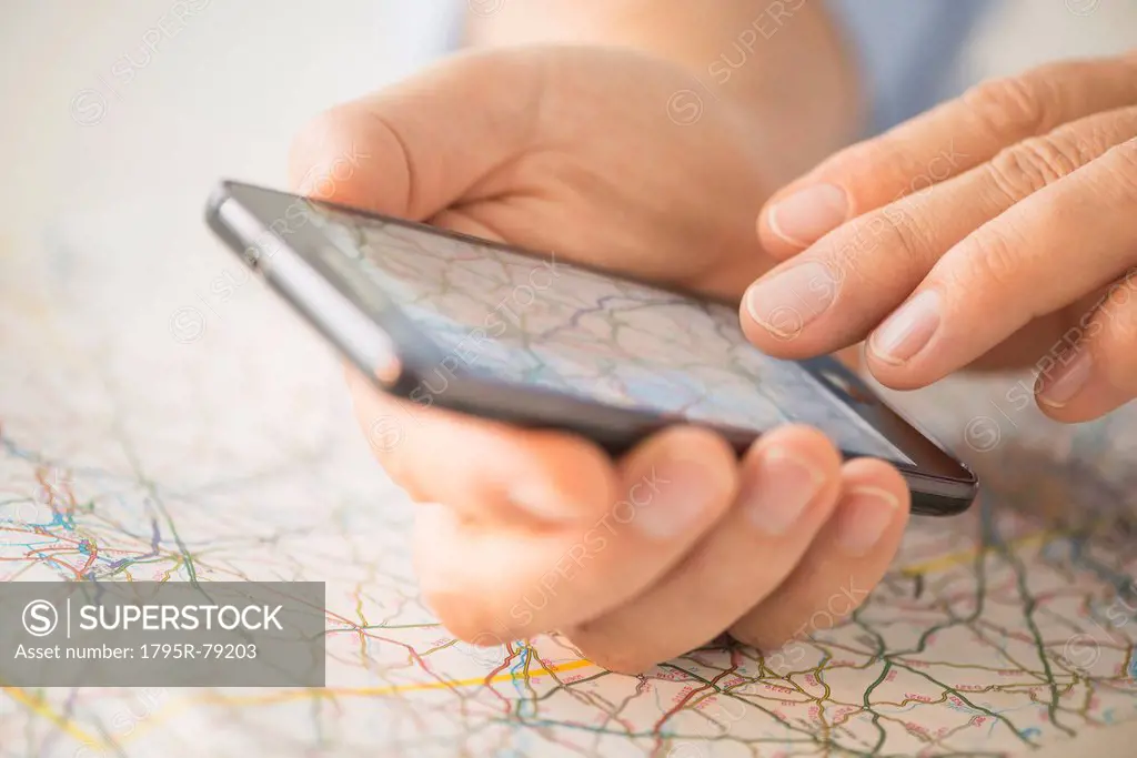 Close_up of hand using smartphone over map